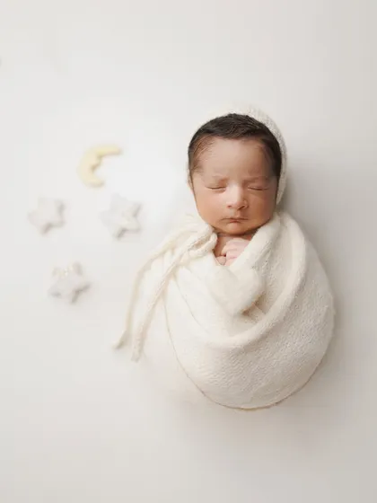 A simple and sweet setup with a classic white wrap and bonnet. The little moon and star props add a touch of magic, creating a dreamy 'Twinkle, Twinkle, Little Star' theme.