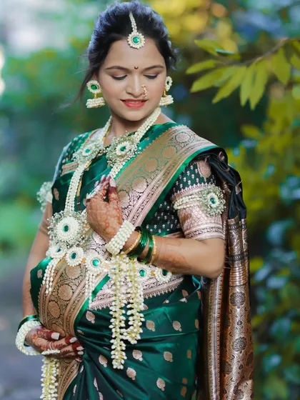 An elegant solo maternity portrait of a mother-to-be, beautifully dressed in a traditional green saree and intricate floral jewelry for her Dohale Jevan ceremony.