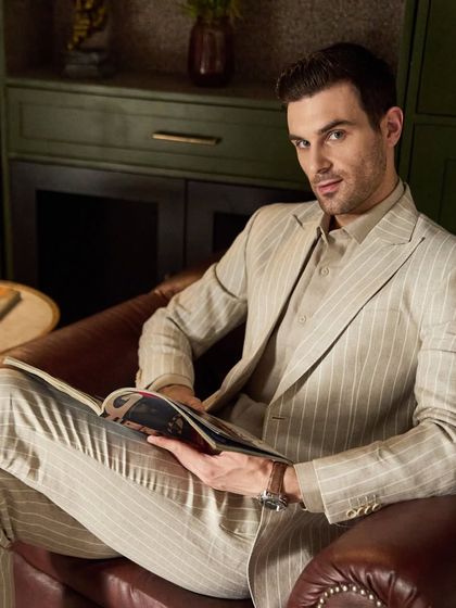 The pinstripe linen suit, seen here in a moment of leisure. The custom fit allows for comfort without sacrificing the sharp, professional aesthetic.