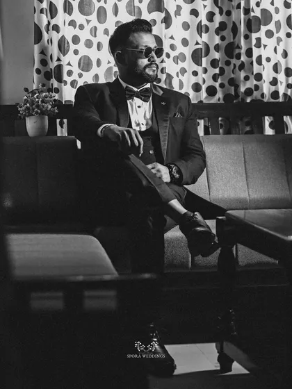 A black and white portrait of the groom looking sharp and sophisticated in his tuxedo and sunglasses.