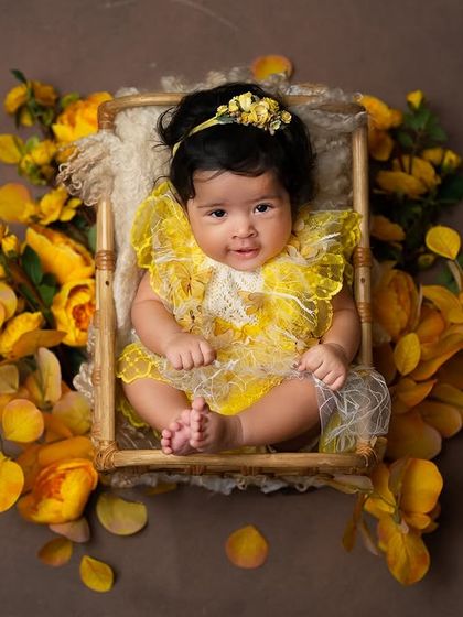 An overhead view of a baby girl in a small bed surrounded by yellow flowers. This shot provides a unique and artistic perspective for a milestone session.