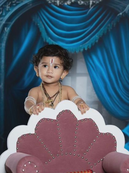 A curious little Krishna peeking over his throne.