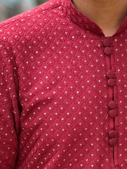 A close-up of a classic red Lucknowi kurta. The fabric-covered buttons and intricate chikankari work showcase the fine details that make our ethnic wear both beautiful and comfortable.