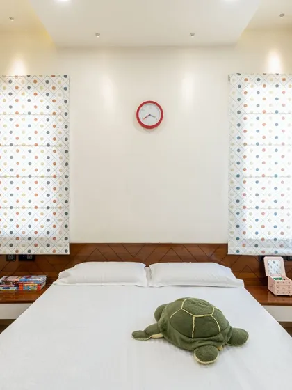 A child's bedroom designed with symmetry in mind, from the matching bedside tables to the polka-dotted roman blinds, creating a calm and orderly space.