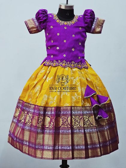 A classic yellow and purple Kanchi Pattu lehenga. The blouse has delicate embroidery, and the skirt has a rich purple and gold border.