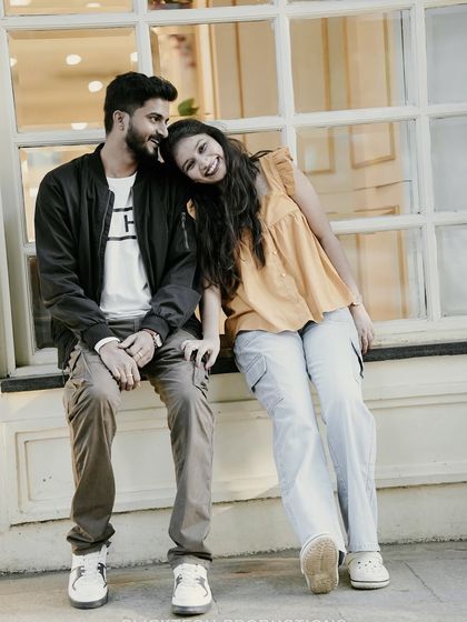 A cute and relaxed photo of a couple sitting on a window ledge, capturing a sweet and casual urban moment.