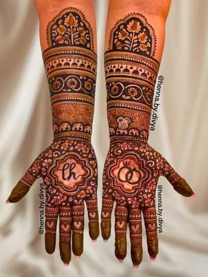 A beautiful example of a full-hand engagement mehendi. This design features the couple's initials 'LH' and a symbol of two rings, surrounded by intricate floral and elephant motifs.