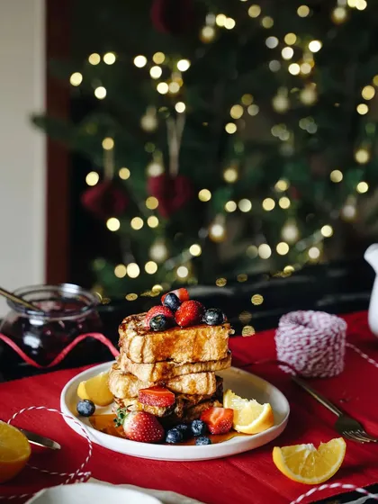 A winter staple on weekends is warm French toast. This shot sets a festive breakfast scene with a Christmas tree in the background and a red table runner.
