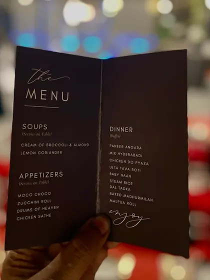 A hand holds up a simple yet elegant menu for a reception dinner. The clear, classic font and layout make it easy for guests to see the delicious options available.