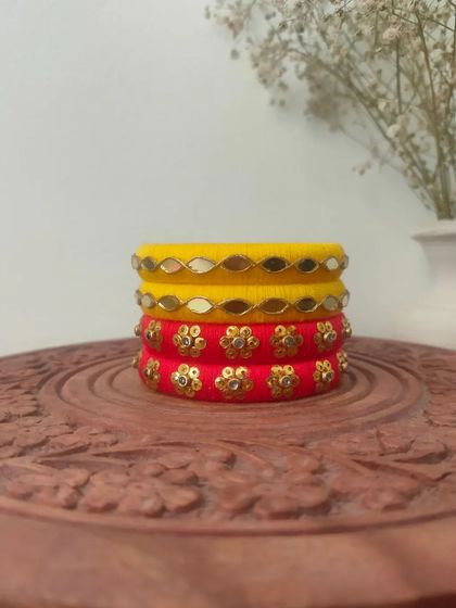 A bright and sunny set of handmade bangles in yellow and red. These are decorated with mirror work and floral sequin patterns, perfect for a Haldi or Mehendi function.
