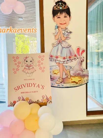 A warm welcome to a special birthday party. This entrance decor features a custom welcome sign and a life-sized caricature cutout of the birthday girl, setting a personalized tone from the very beginning.