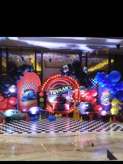 A high-speed Hot Wheels and Cars themed birthday party. The setup includes a checkered flag floor, a custom backdrop with the birthday boy's name, and character cutouts of Lightning McQueen.