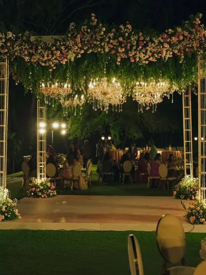 A wide view of the elegant evening reception, showcasing the guest seating and the beautifully lit floral canopy.