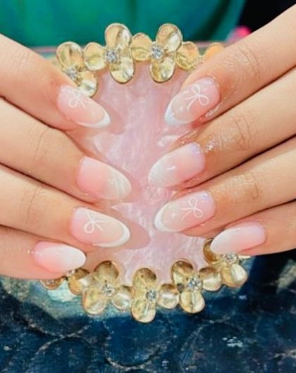 A delicate and subtle design featuring a soft white ombre effect with tiny, hand-painted white bows on the tips.