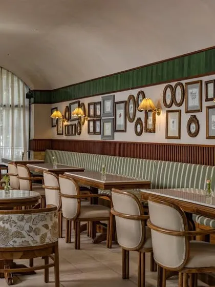 The cafe's interior features a gallery wall of framed pictures and custom upholstery, adding a personal and curated touch to the space.
