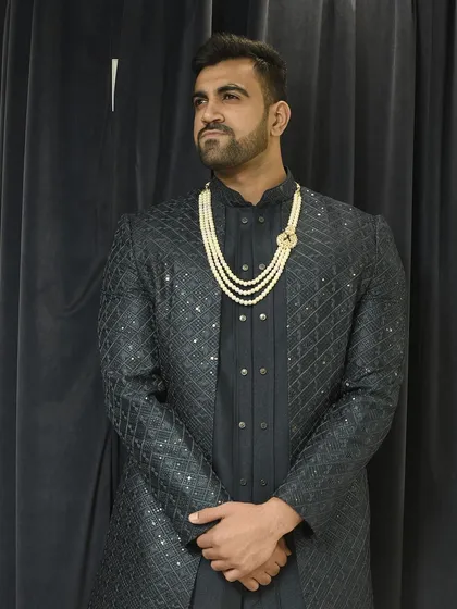 Our "desi look" featuring a textured black Indo-western jacket over a matching kurta, elevated with a multi-strand pearl mala. This is a client favorite for its sharp and royal feel.
