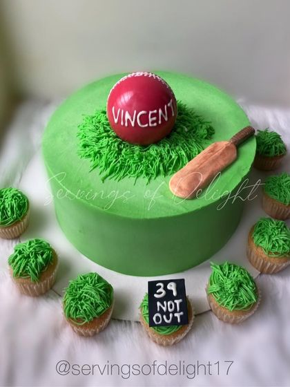 A cricket-themed cake and matching cupcakes for a sports lover. The cake is designed to look like a cricket pitch, complete with a bat, ball, and wickets.
