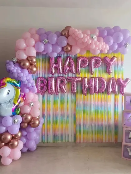The full unicorn party setup, including a rainbow fringe curtain and "BABY" blocks, perfect for a first birthday or baby shower.