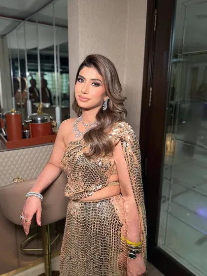 A moment of elegance by the bar. Her makeup is flawless, with soft waves in her hair completing this sophisticated evening look.