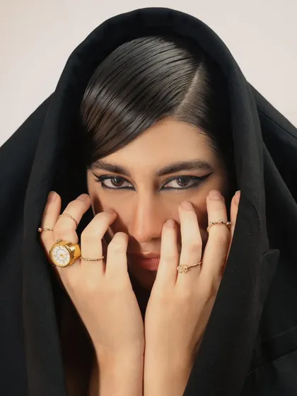 An intimate, mysterious close-up where the model's jacket creates a hood. The focus is on the eyes and the dramatic makeup, creating a captivating beauty shot.