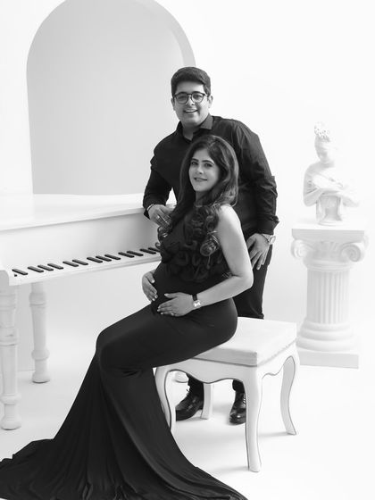 An elegant and classic studio portrait. The piano and pedestal add a touch of timeless sophistication to this beautiful black and white couple's maternity photo.