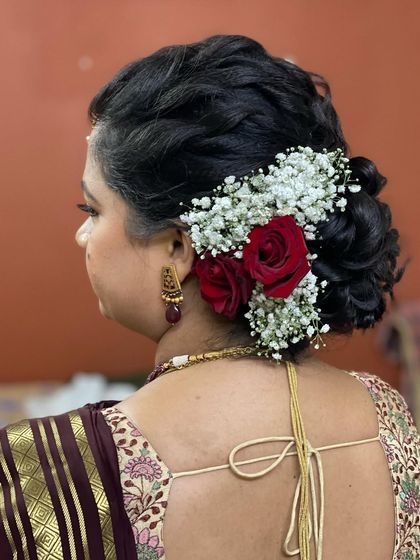 A detailed view of the messy bun hairstyle with fresh roses and baby's breath, a perfect choice for a pre-wedding ceremony.