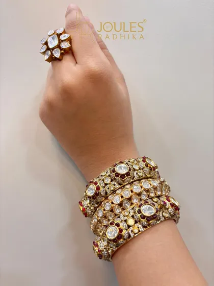 A stack of ornate kundan and ruby bangles paired with a floral polki ring, a classic combination for any bride.