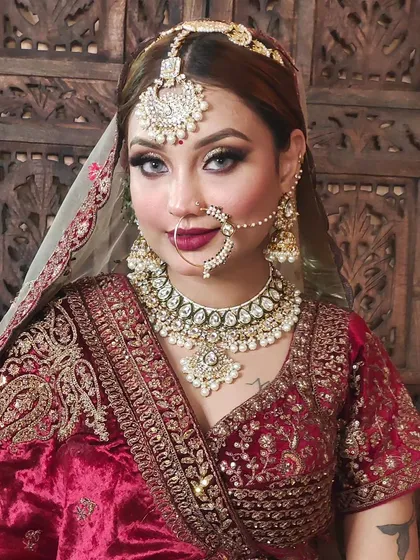 A detailed look at a bridal set featuring a heavy Polki choker, maang tikka, and nath, paired with a classic red embroidered blouse.