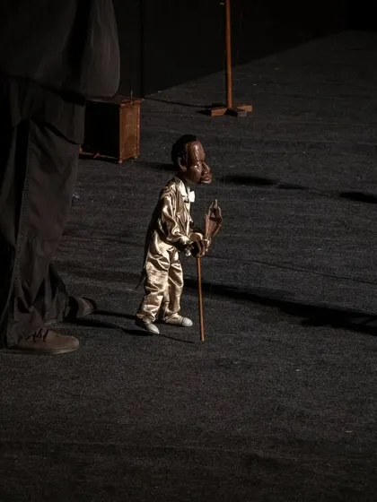 An elderly character marionette from 'Il Fil'armonico' takes a walk on stage. The puppet's posture and movement tell a story of a long life lived.