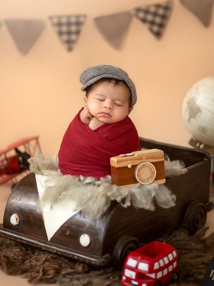 Our little traveler, Ridhaan, is ready for his journey, sleeping in a vintage car prop with a newsboy cap and a tiny wooden camera.
