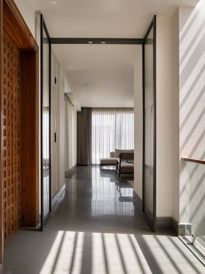A view down the central corridor, where light from the skylight stripes the floor. The polished Kota stone reflects the light, enhancing the sense of brightness in this compact home.