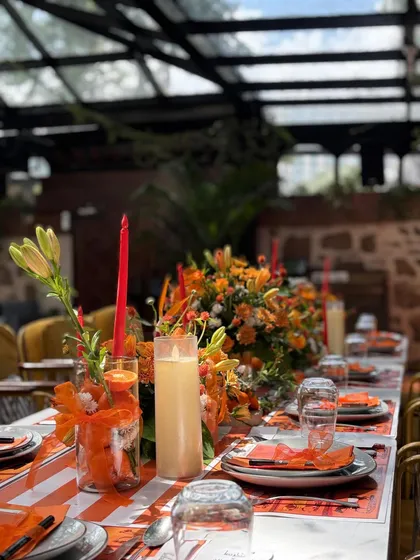 A long shot of the stunning tablescape for the Hermès-themed brunch. The vibrant orange flowers, candles, and custom placemats created a warm and inviting atmosphere.