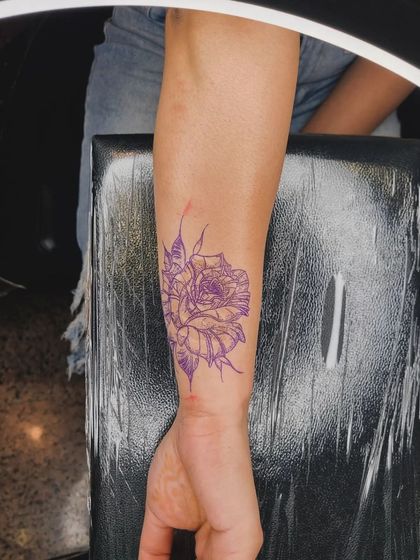 The purple stencil of the rose design placed over the scar, mapping out the tattoo before the ink is applied.