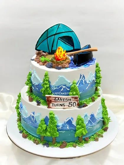 A two-tier cake for a 50-year-old who loves trekking and camping. The design features a tent, a campfire, and a mountain scene.
