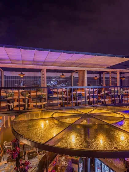 The upper deck of the rooftop bar at night, with its retractable canopy pulled back. This space is designed to feel like a sophisticated lounge, with clear views of the sky.