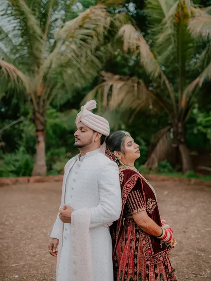 An artistic back-to-back pose, showcasing the couple's elegant reception outfits against a natural backdrop.