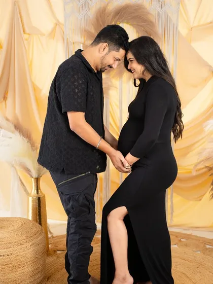 A sweet and simple couple's pose. Dressed in matching black, they hold hands and touch foreheads, creating an intimate silhouette against our warm, neutral backdrop.