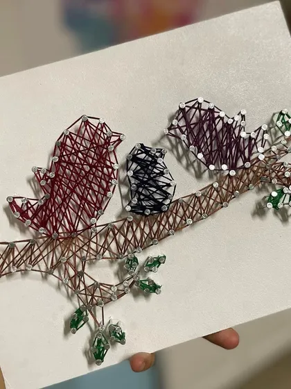 A close-up of the "Family of Birds" string art, showcasing the detailed weaving and color choices.