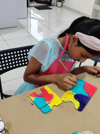 This girl is focused on painting a multi-colored design on her wooden calendar stand during an art birthday party.