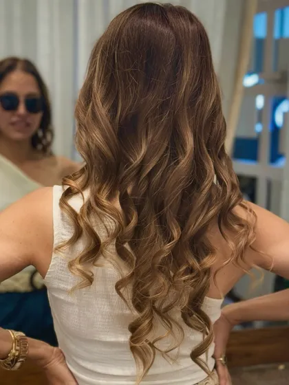 A final look at this client's beautiful hair transformation. The mirror reflection shows her satisfaction, and the back view highlights the flawless curls and rich color.