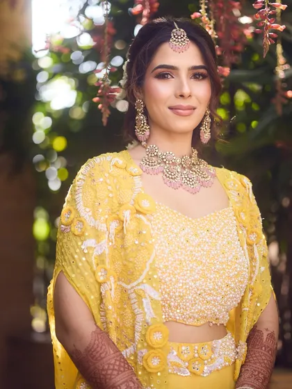 A portrait of our Haldi bride. The soft pink tones in her makeup and jewelry beautifully complement her yellow outfit.