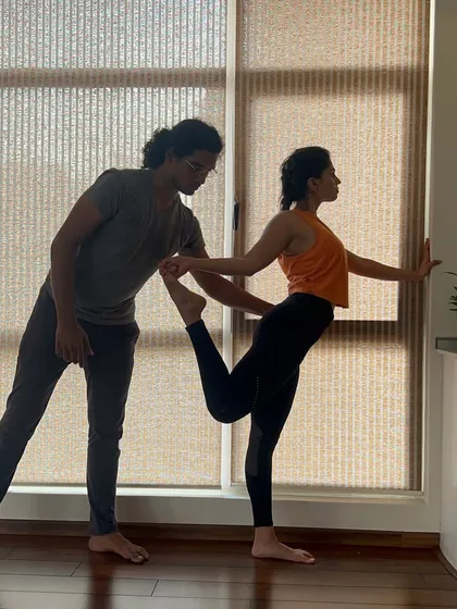 Finding the balance between effort and ease in Natarajasana, the dancer's pose. A teacher's steadying hand provides the confidence to explore the full extension of the pose, deepening the stretch in the shoulders and chest.