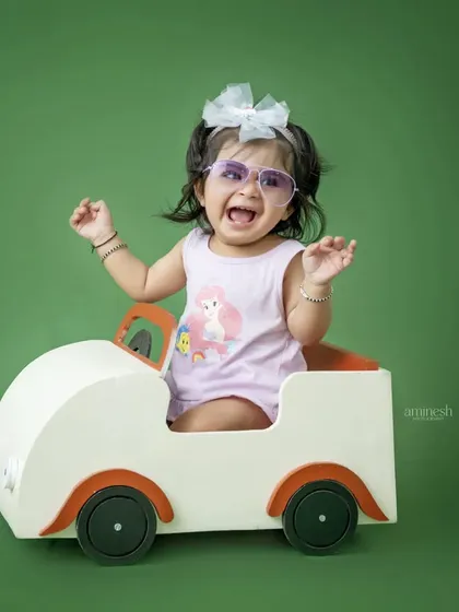 A moment of pure, unscripted fun as a little girl in sunglasses laughs while sitting in a toy car. I love capturing these real, candid expressions during my sessions.
