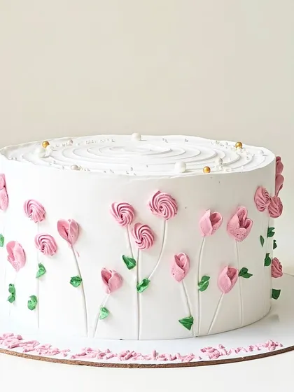 A simple white cake adorned with delicate pink buttercream tulips. This minimalist design focuses on clean lines and the beauty of hand-piped floral art.