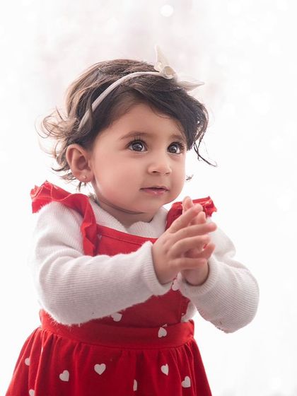 Through the lens, cuteness unfolds. A simple, high-key portrait of a little girl in a red dress, her expression full of innocence.