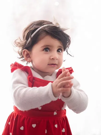 Through the lens, cuteness unfolds. A simple, high-key portrait of a little girl in a red dress, her expression full of innocence.