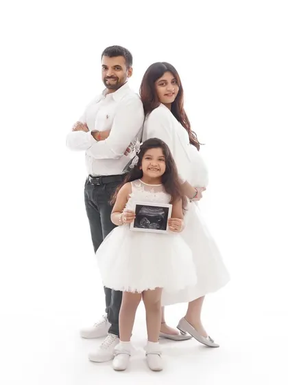 A stylish and modern family pregnancy announcement. The pose is confident and happy, showing a family united and excited for their new addition.