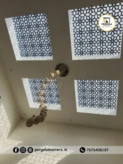 Four square skylights with a geometric jali pattern are arranged in the ceiling, centered around a modern chandelier. This design integrates natural and artificial light sources into a cohesive and elegant ceiling feature.