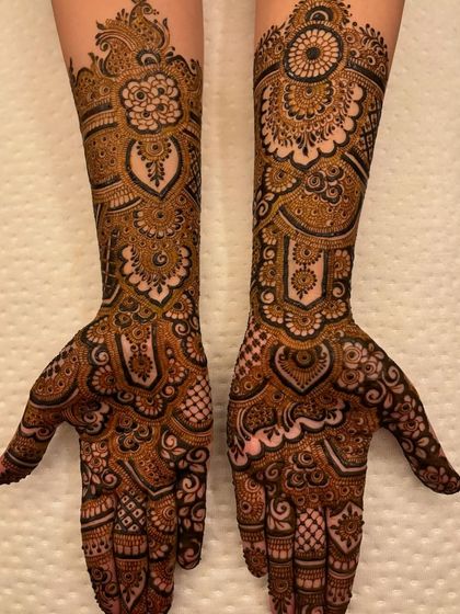 A stunning example of a symmetrical design, where both hands mirror each other with intricate heart shapes, florals, and detailed finger work.
