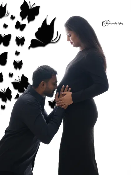 A creative studio shot with a butterfly theme. The father-to-be kisses the baby bump, framed by edited-in butterflies.